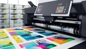 Close-up of a digital printing machine producing colorful prints on paper in a print shop.